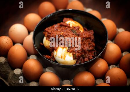 Nahaufnahme Von Egg Curry In Black Pot. Hintergrund Gefüllt Mit Frischen Eiern Stockfoto