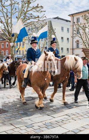 Reiter mit blauen und weißen Fahnen auf dekorierten Pferden bei der St. Georgspilgerfahrt Georgiritt in Traunstein am Ostermontag in Bayern Stockfoto