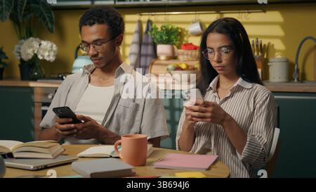 Multirassische Teenager High School Schüler Guy Girl Afroamerikaner Mann Arabische Frau ignoriert das Surfen von Smartphones Online-Shopping in der Küche zu Hause Stockfoto