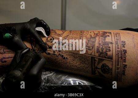 Beirut, Beirut, Libanon. Mai 2025. Ein Künstler färbt ein Tattoo mit dem Thema des 05. August 2020 Beirut massiver Hafenschlag auf das Bein einer libanesischen Jugend, Elie, während eines Tätowierfestivals in Beirut. Die Tätowierung soll an das traumatische Ereignis erinnern, bei dem mindestens 200 Menschen getötet und tausende andere verletzt wurden. Die Tätowierungskultur im Libanon hat in den letzten Jahren stetig zugenommen, und im Vergleich zum Rest der Region im Nahen Osten ist Tätowierung in Beirut weniger tabu als je zuvor. (Kreditbild: © Marwan Naamani/ZUMA Press Wire) NUR REDAKTIONELLE VERWENDUNG! Nicht für kommerzielle ZWECKE! Stockfoto