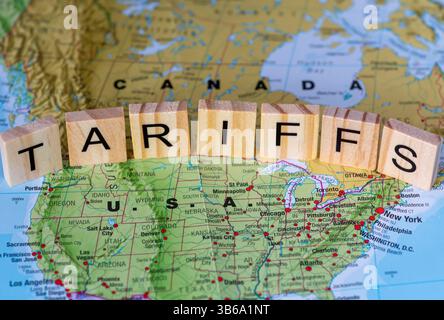 Eine Karte der USA und Kanadas mit Holzziegeln, die das Wort Zölle zwischen den beiden Ländern bilden. Ein Konzept für Handelszölle in Kanada und den USA. Stockfoto