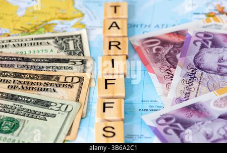 Buchstaben Holzfliesen auf einer Karte, die das Wort Tarife mit US-Dollar-Scheinen und Pfund Sterling-Banknote auf jeder Seite bilden. Ein US-amerikanischer Staat, Vereinigtes Königreich Stockfoto