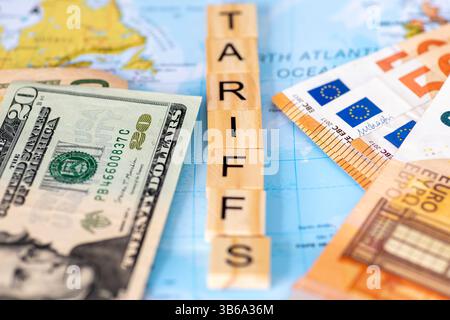 Buchstaben Holzfliesen auf einer Karte, die das Wort Tarife mit US-Dollar-Scheinen und Euro-Banknote auf jeder Seite bildet. USA, EU-Handelszölle Stockfoto
