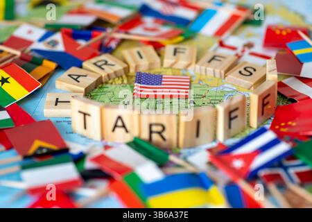 Buchstaben Holzfliesen, die die Worte „Zölle“ bilden, die eine Karte der Vereinigten Staaten von Amerika mit Flaggen anderer Länder umgeben. Ein US-Handelstarif Stockfoto