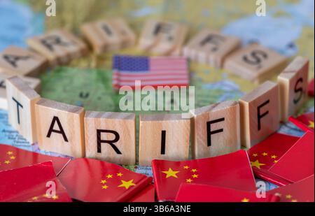 Buchstaben Holzfliesen, die die Worte Zölle bilden, die eine Karte der Vereinigten Staaten von Amerika umgeben, mit Flaggen von China draußen. A Handelszölle der USA und Chinas c Stockfoto