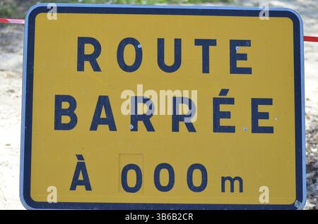 Straßensperrschild in französischer Sprache mit auffälligen schwarzen Buchstaben auf hellgelbem Hintergrund, die Fahrer auf bevorstehende Fahrten aufmerksam machen Stockfoto