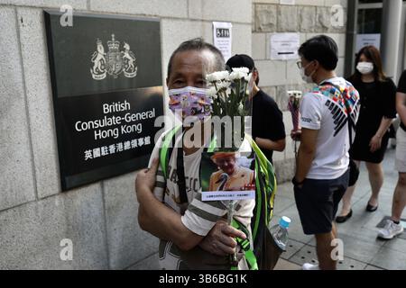 12. September 2022, HONGKONG, CHINA: Ein Mann mit einem Blumenstrauß und dem Foto der verstorbenen Königin Elisabeth II. Wartet darauf, in das britische Generalkonsulat in Hongkong einzutreten, um das Kondolenzbuch zu unterschreiben.12. September 2022 Hong Kong.ZUMA/Liau Chung-ren (Kreditbild: © Liau Chung-ren/ZUMA Press Wire) Stockfoto