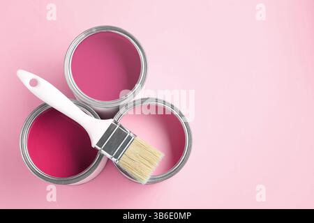 Dosen mit Farbe in Rosa und Pinsel auf farbigem Hintergrund, Draufsicht. Leerzeichen für Text Stockfoto