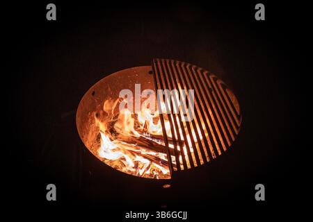 Ein Lagerfeuer brennt hell in einem Feuerrost in einer dunklen Nacht. Stockfoto