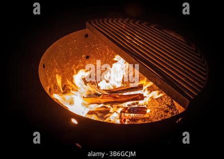 Ein Lagerfeuer brennt hell in einem Feuerrost in einer dunklen Nacht. Stockfoto