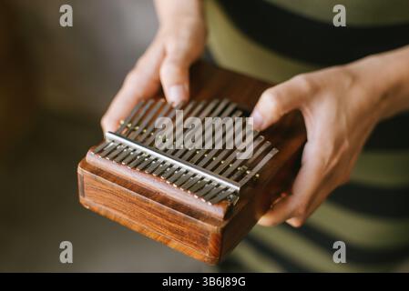 Nahaufnahme der Hände, die ein hölzernes Kalimba-Musikinstrument halten. Stockfoto