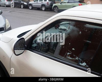 Cremona, Italien - 12. April 2025 Nahaufnahme des weißen Nissan Juke SUV Innen- und Außendetails mit Regentropfen am Fenster, Ansicht der Lenkung Stockfoto