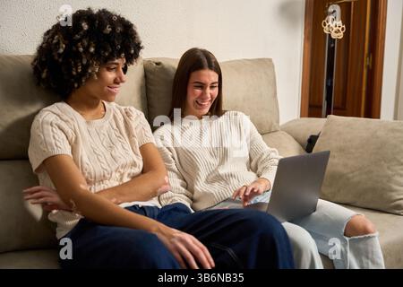 Zwei Studentinnen, die sich zu Hause ein lustiges Video auf einem Laptop anschauen Stockfoto