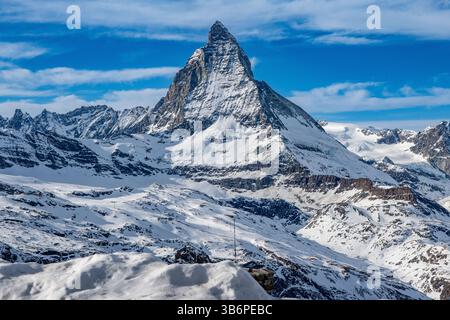 Das berühmte Matterhorn erhebt sich majestätisch über den verschneiten Alpen, dessen scharfer Gipfel sich in den blauen Himmel zieht – eine atemberaubende Winterszene Stockfoto