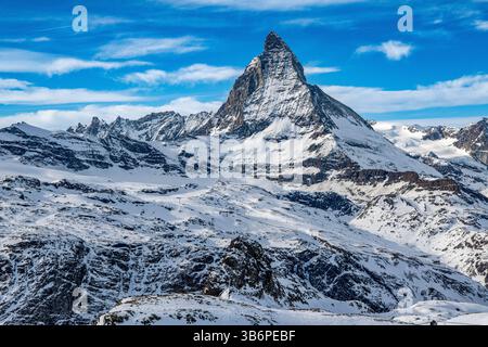 Das berühmte Matterhorn erhebt sich majestätisch über den verschneiten Alpen, dessen scharfer Gipfel sich in den blauen Himmel zieht – eine atemberaubende Winterszene Stockfoto