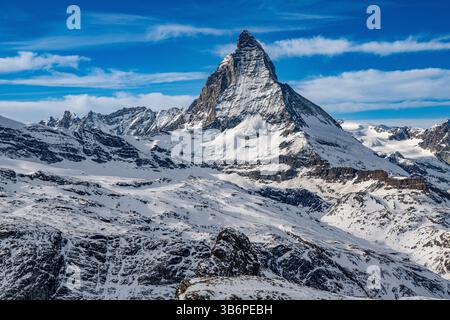 Das berühmte Matterhorn erhebt sich majestätisch über den verschneiten Alpen, dessen scharfer Gipfel sich in den blauen Himmel zieht – eine atemberaubende Winterszene Stockfoto