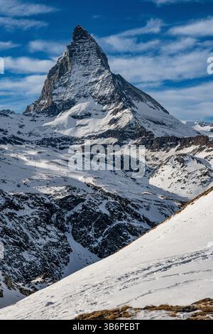 Das berühmte Matterhorn erhebt sich majestätisch über den verschneiten Alpen, dessen scharfer Gipfel sich in den blauen Himmel zieht – eine atemberaubende Winterszene Stockfoto