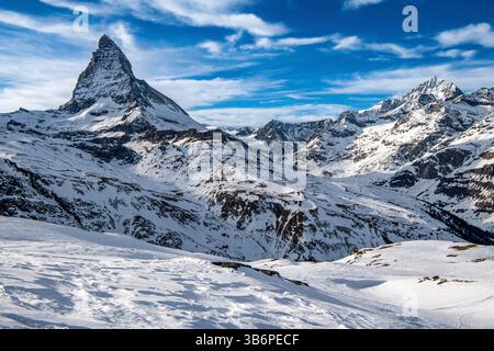 Das berühmte Matterhorn erhebt sich majestätisch über den verschneiten Alpen, dessen scharfer Gipfel sich in den blauen Himmel zieht – eine atemberaubende Winterszene Stockfoto