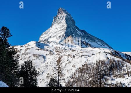 Das berühmte Matterhorn erhebt sich majestätisch über den verschneiten Alpen, dessen scharfer Gipfel sich in den blauen Himmel zieht – eine atemberaubende Winterszene Stockfoto