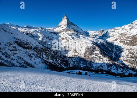 Das berühmte Matterhorn erhebt sich majestätisch über den verschneiten Alpen, dessen scharfer Gipfel sich in den blauen Himmel zieht – eine atemberaubende Winterszene Stockfoto