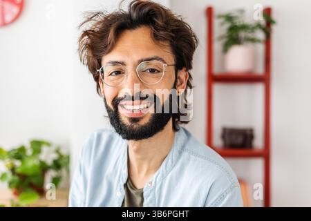 Lächelndes Porträt eines jungen bärtigen professionellen Designers, der in die Kamera schaut Stockfoto