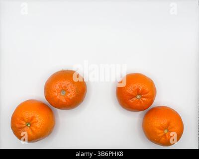 4 leuchtend orange Mandarinen ganz in der Bildmitte auf weißem Hintergrund Draufsicht Stockfoto