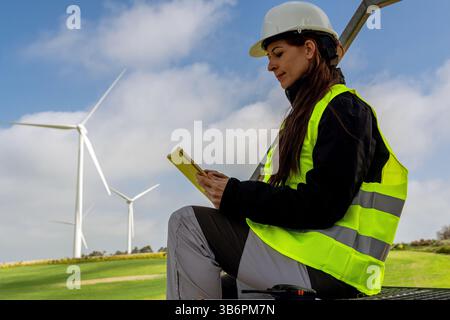 Ingenieurin mit digitalem Tablet, das in Windkraftwerken arbeitet und nachhaltige Energie erzeugt Stockfoto