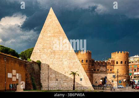 Blick auf die Pyramide von Cestius und Porta San Paolo in Rom, Italien, unter dunklem Himmel vor einem Sturm.​ Stockfoto