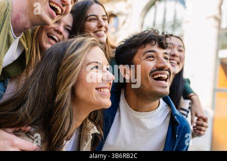 Glückliche Gruppe junger Studenten, die sich umarmen und draußen lachen. Stockfoto