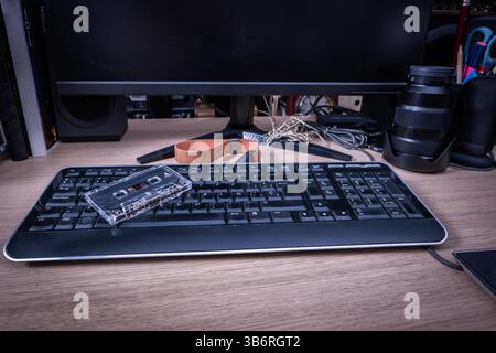 Transparente Audiokassette, die auf einer Computertastatur liegt, zeigt den Kontrast zwischen klassischer und moderner Technologie Stockfoto