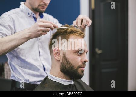 Friseur, Frisur bärtiger Mann im Barbershop. Professionelle Stylisten schneiden client Haar im Salon. Friseur mit einer Schere und Kamm. Geschickte hairdress Stockfoto