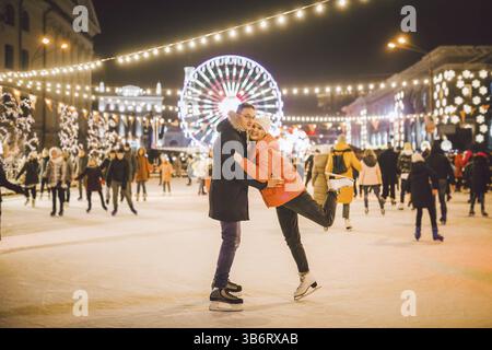 Wunderschönes Paar Schlittschuhlaufen Im Stadtzentrum. Ein junges Paar, das draußen auf einer öffentlichen Eislaufbahn läuft. Schlittschuhbahn und liebevolles Paar. Ama Stockfoto