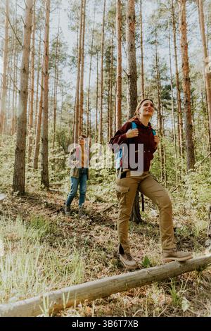 Zwei Abenteurer wandern auf einem Waldweg, während ihr Geist durch das üppige Baumdach gleitet und ihre gemeinsame Reise beleuchtet. Stockfoto