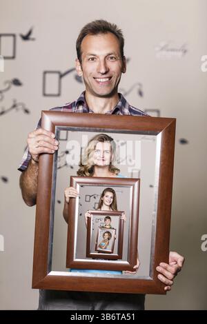Glücklicher Vater hält Porträt mit seiner Familie jeder befindet sich in ihren eigenen Rahmen Stockfoto
