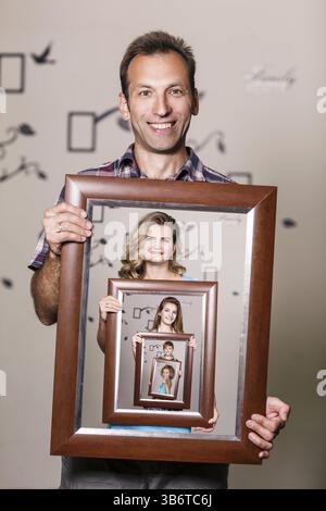 Glücklicher Vater hält Porträt mit seiner Familie jeder befindet sich in ihren eigenen Rahmen Stockfoto