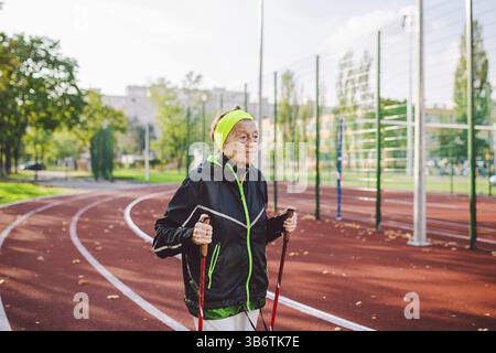Aktiver Rest des Themas „ältere Menschen“. Sport und Gesundheit im Ruhestand. Kaukasische sehr alte Frau mit tiefen Falten, die Nordic Walking Übungen mit sti macht Stockfoto