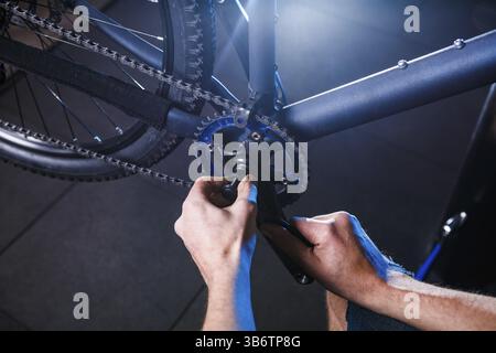 Eine Nahaufnahme der Hand eines männlichen Fahrradmechaniker in der Werkstatt verwendet einen Schraubendreher Werkzeug an das Fahrrad Handkurbel, Reparieren und Einstellen der vorderen Rad s Stockfoto