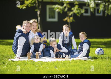 Große Familie entspannen Sie in der grünen Natur. Happy Family Portrait auf Outdoor, Gruppe 6 Leute sitzen auf Gras, Sommer, Kind und Elternteil. Kinder, runde Klammer Stockfoto