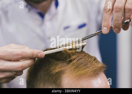 Friseur, Frisur bärtiger Mann im Barbershop. Professionelle Stylisten schneiden client Haar im Salon. Friseur mit einer Schere und Kamm. Geschickte hairdress Stockfoto