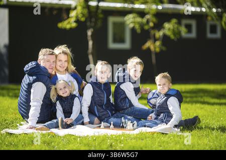 Große Familie entspannen Sie in der grünen Natur. Happy Family Portrait auf Outdoor, Gruppe 6 Leute sitzen auf Gras, Sommer, Kind und Elternteil. Kinder, runde Klammer Stockfoto