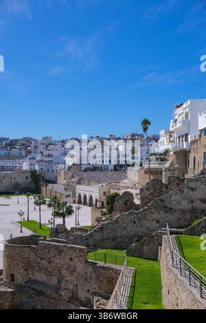 Die alten Stadtmauern von Tanger umrahmen einen modernen Hafen und einen neuen städtischen Platz, eine lebendige Mischung aus Geschichte und Fortschritt unter einem klaren blauen Himmel. Stockfoto
