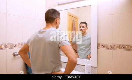 Mann, der unter Augenflecken für dunkle Ringe aufträgt Stockfoto