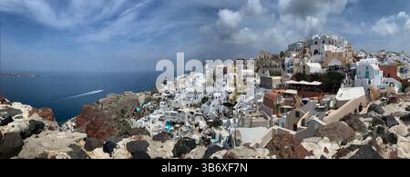 Santorin, Griechenland - 31. Mai 2023: Panoramablick auf die weiß getünchten Gebäude und die bunten Dächer von Oia, Santorin, mit Blick auf die Ägäis. Stockfoto