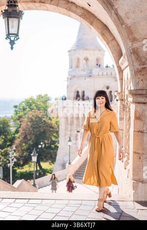 Eine selbstbewusste Frau genießt die Aussicht von der Fishermans Bastion in Budapest und repräsentiert weibliche Alleinreisen, Freiheit und kulturelle Entdeckungen. Stockfoto