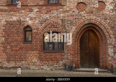Historische Ziegelfassade mit Bogeneingang und kleinen Fenstern in Ystad, Schweden. Mittelalterliche architektonische Details. Stockfoto