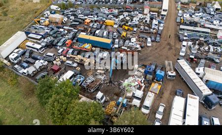 Aus der Vogelperspektive auf einen überfüllten Schrottplatz mit zahlreichen Autos, Lastwagen und Schrott. Stockfoto