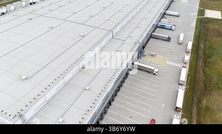 Aus der Vogelperspektive eines großen Industrielagers mit mehreren Laderampen und geparkten Lkws. Stockfoto