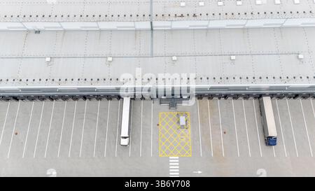 Aus der Vogelperspektive eines großen Industrielagers mit zwei Lkw, die an Laderampen geparkt sind. Stockfoto