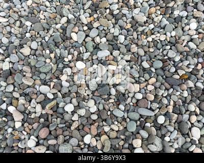 Blick von oben auf farbenfrohe, glatte Kieselsteine an einem Strand, typisch für Reiseziele am Meer. Natursteinstruktur, abstraktes Muster, keine Menschen. Stockfoto