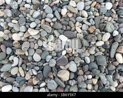 Blick von oben auf glatte gemischte Kieselsteine an einem natürlichen Strand. Küstenstruktur und abstrakter Hintergrund, keine Menschen, Reisen und Naturthemen. Stockfoto
